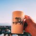 A hand holding a motivational mug with 'Make Mistakes' against a sunset in Lviv.