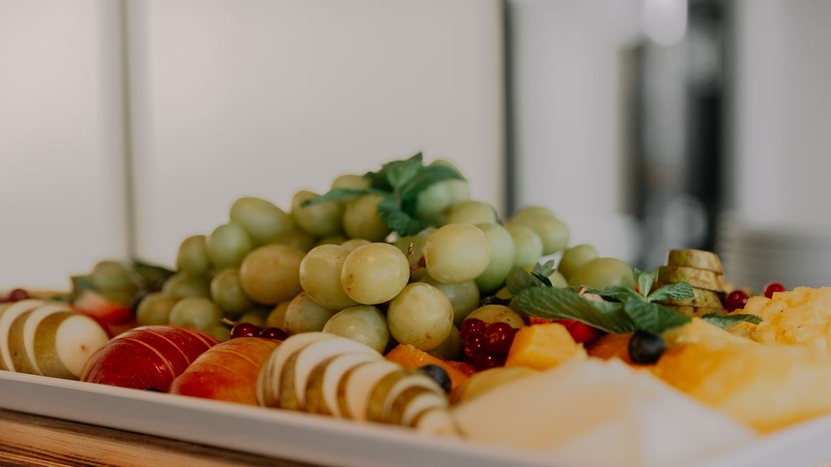 A vibrant assortment of fruits including grapes, apples, and berries on a white tray.
